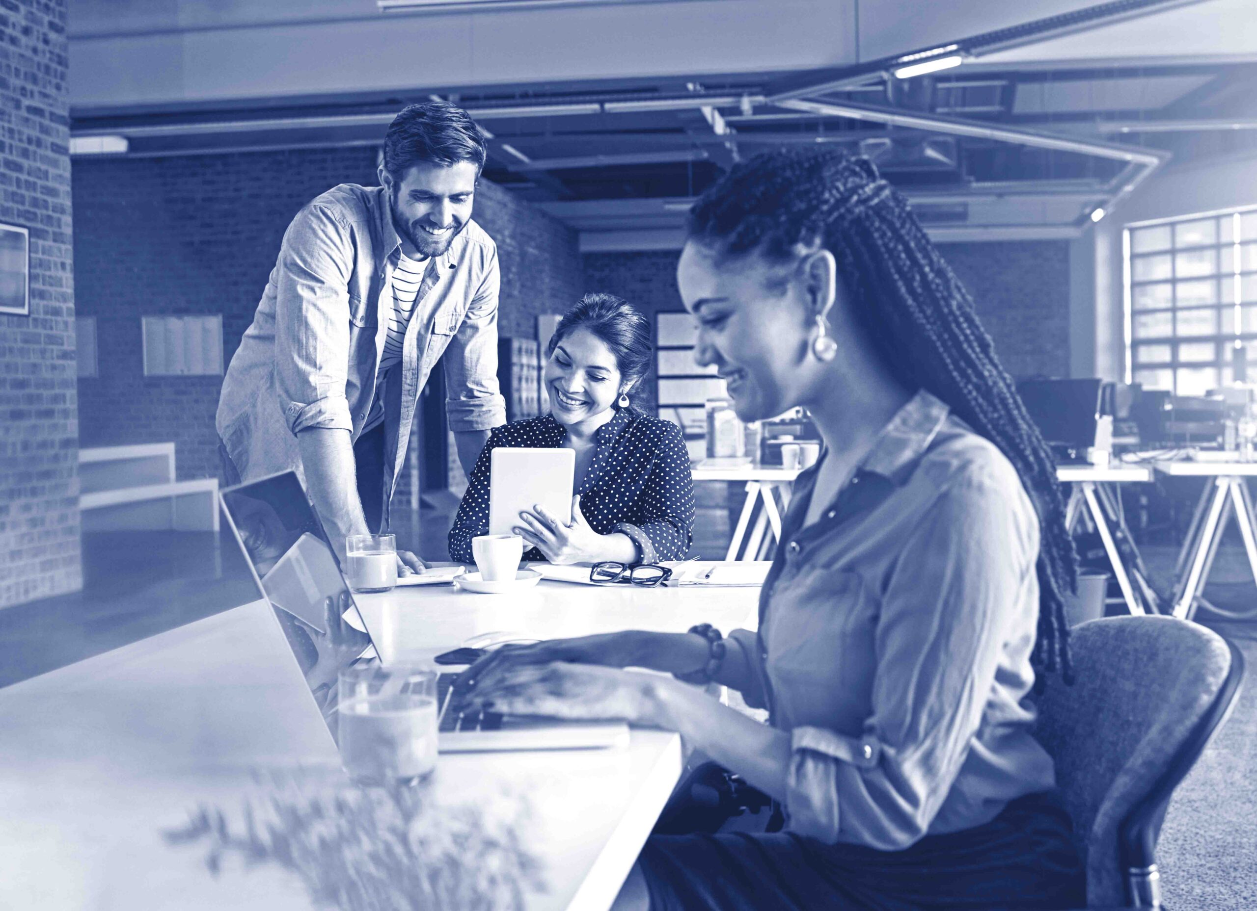 Making a success of of their startup. Shot of a young woman working on a laptop with her colleagues in the background.